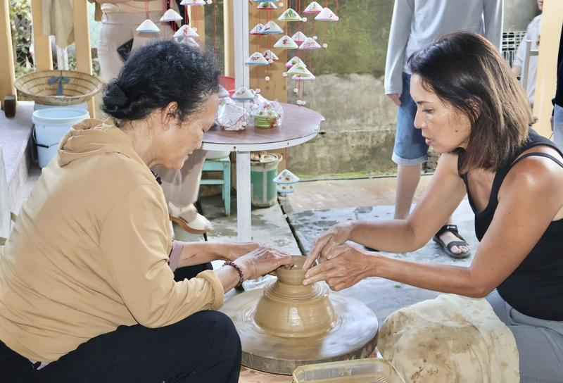 Du khách được các nghệ nhân hướng dẫn, trực tiếp trải nghiệm các công đoạn như xoay bàn gốm, tạo hình, nặn sản phẩm. Ảnh: Diễm Phúc