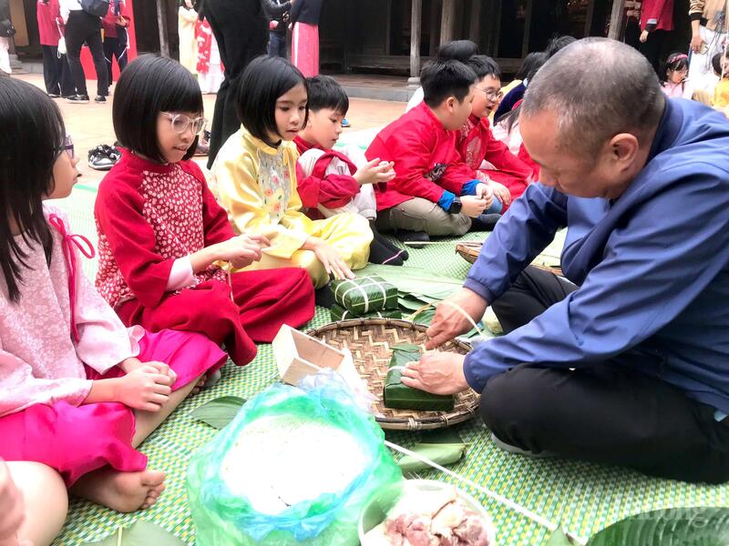 Các nghệ nhân hướng dẫn học sinh gói bánh chưng ngày Tết. Ảnh: Hoa Quỳnh